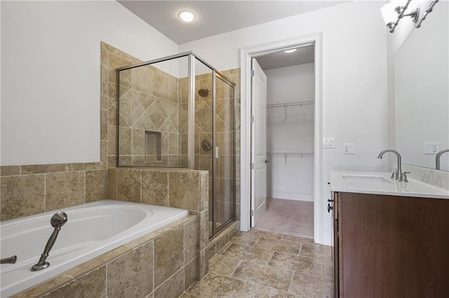full bath with a stall shower, a walk in closet, a bath, and vanity