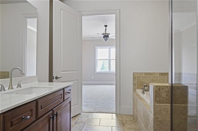 full bath with ceiling fan, vanity, a relaxing tiled tub, and baseboards