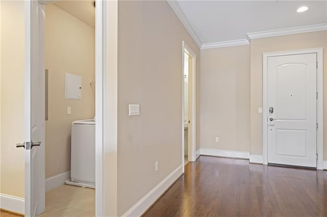 hallway featuring washer / dryer, baseboards, wood finished floors, and ornamental molding