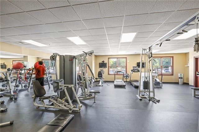 exercise room with plenty of natural light, a drop ceiling, and baseboards