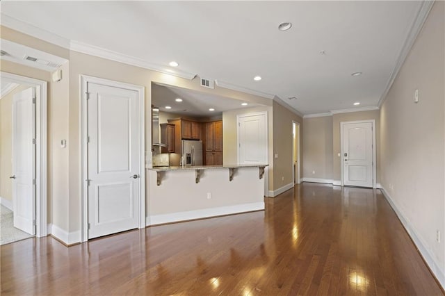 unfurnished living room featuring hardwood / wood-style floors, baseboards, ornamental molding, and recessed lighting