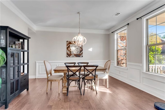 dining room with a notable chandelier, ornamental molding, and hardwood / wood-style flooring