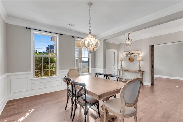 dining area with crown molding, a chandelier, and hardwood / wood-style floors