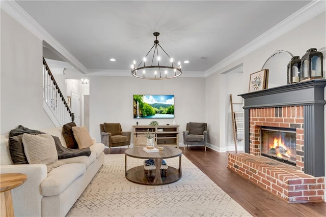 living room featuring a fireplace, ornamental molding, hardwood / wood-style flooring, and a chandelier