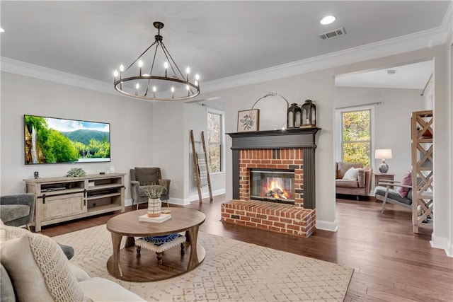 living room with a brick fireplace, hardwood / wood-style floors, and ornamental molding