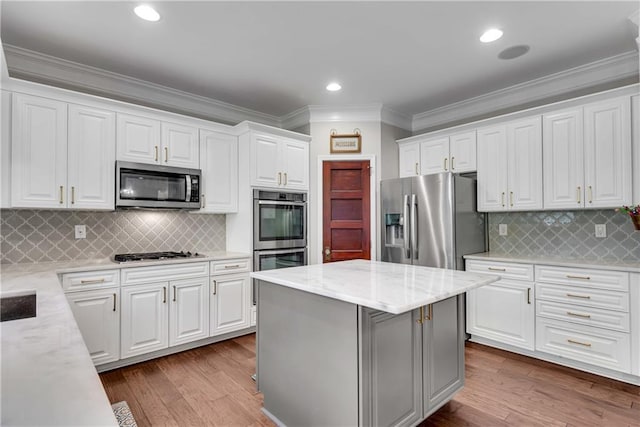 kitchen featuring a kitchen island, white cabinetry, light stone counters, and appliances with stainless steel finishes