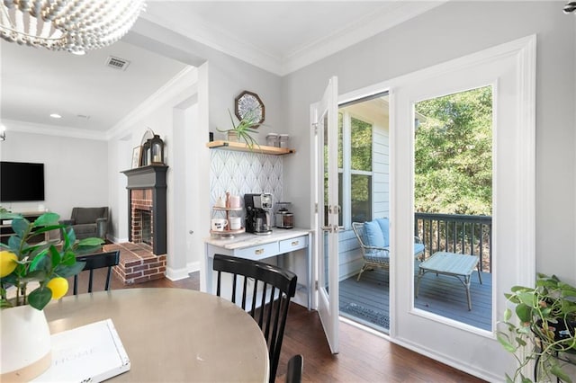 dining room with a fireplace, a chandelier, crown molding, and dark hardwood / wood-style floors