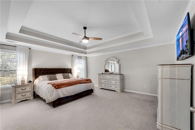 bedroom with light carpet, ceiling fan, and a tray ceiling