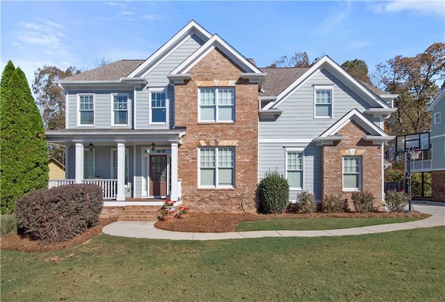 view of front of home featuring a front lawn, a porch, and brick siding