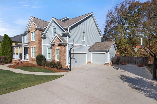 traditional home featuring driveway, an attached garage, fence, a front lawn, and brick siding