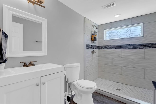 bathroom featuring vanity, toilet, wood-type flooring, and a tile shower