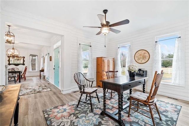 dining space featuring healthy amount of natural light, a ceiling fan, ornamental molding, a chandelier, and light wood finished floors