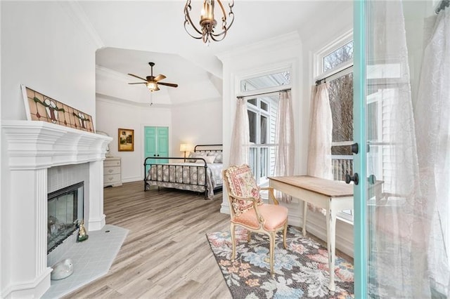 office space featuring crown molding, a ceiling fan, wood finished floors, a chandelier, and a glass covered fireplace