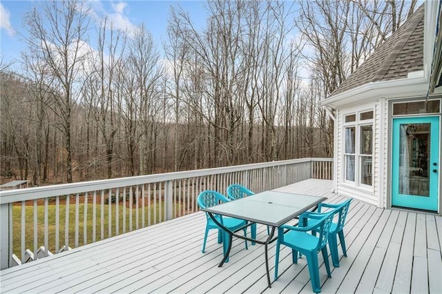 wooden terrace featuring outdoor dining area and a yard