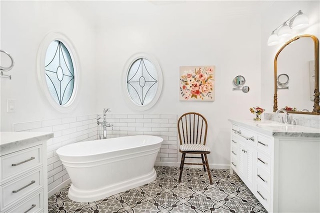 full bathroom featuring vanity, a freestanding bath, tile walls, wainscoting, and tile patterned flooring