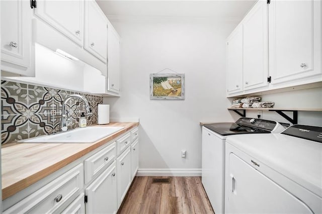 laundry area with washing machine and clothes dryer, wood finished floors, cabinet space, and baseboards