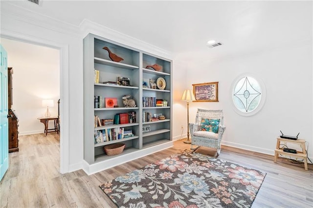 sitting room featuring wood finished floors, baseboards, and ornamental molding