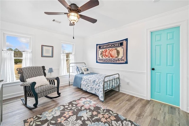 bedroom with multiple windows, crown molding, wood finished floors, a ceiling fan, and baseboards