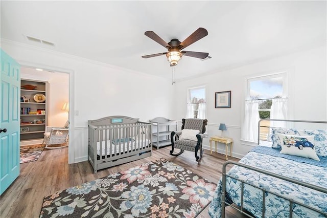 bedroom featuring wood finished floors, crown molding, a ceiling fan, and baseboards