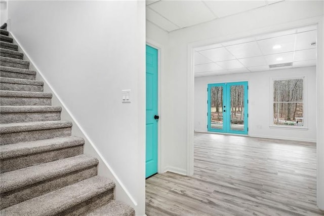staircase featuring a drop ceiling, wood finished floors, french doors, baseboards, and recessed lighting