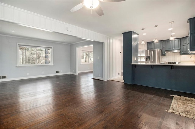 unfurnished living room with dark wood-type flooring, a ceiling fan, baseboards, visible vents, and crown molding