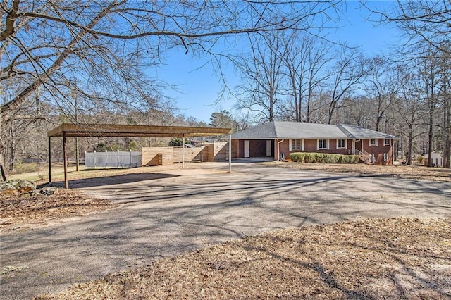 view of front of property with a carport, aphalt driveway, fence, and brick siding