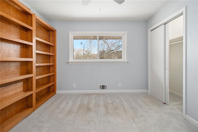 unfurnished bedroom with a closet, light carpet, visible vents, and baseboards