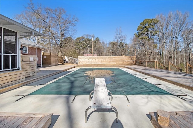 view of pool featuring a diving board, a fenced in pool, and a wooden deck