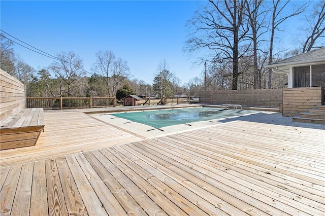 view of swimming pool with a fenced in pool, a fenced backyard, a deck, and a diving board