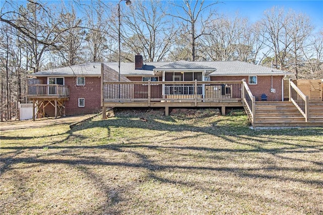 rear view of house with brick siding, a yard, a chimney, and a wooden deck