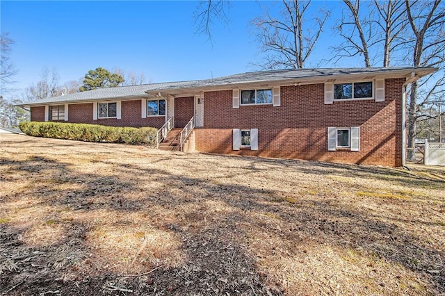 ranch-style home with entry steps, brick siding, and a front yard