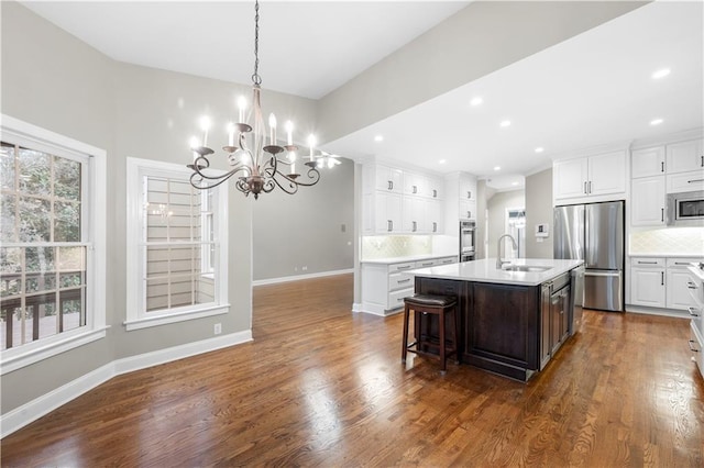 kitchen with dark wood-style flooring, stainless steel appliances, a sink, and light countertops