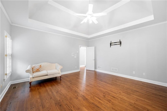 unfurnished room with wood finished floors, a raised ceiling, visible vents, and baseboards