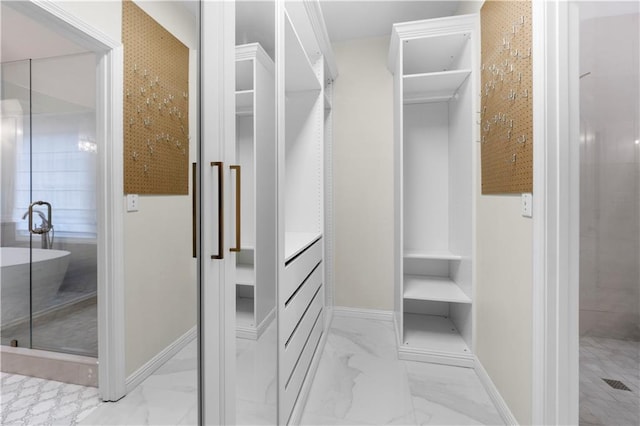 walk in closet featuring marble finish floor