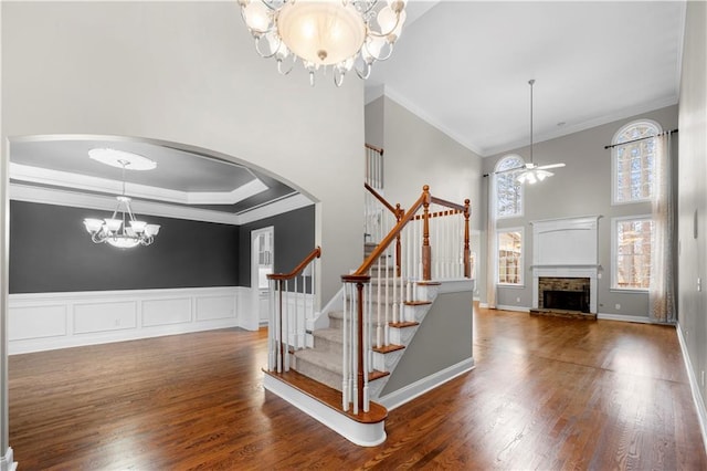 entryway featuring a fireplace, arched walkways, wood finished floors, and ornamental molding