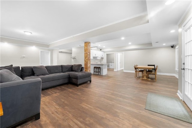 living room featuring baseboards, ornamental molding, wood finished floors, and recessed lighting