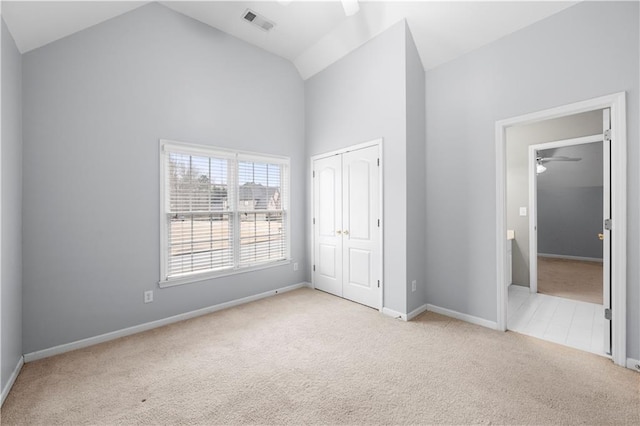 unfurnished bedroom featuring baseboards, visible vents, carpet flooring, high vaulted ceiling, and a closet