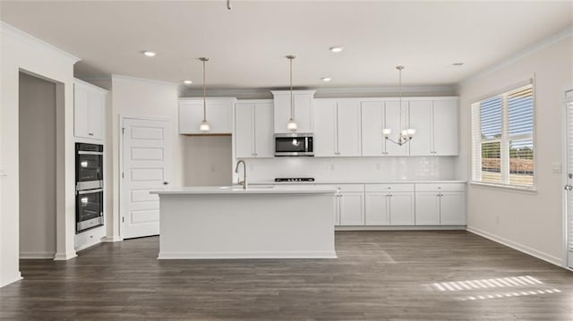 kitchen featuring a center island with sink, appliances with stainless steel finishes, pendant lighting, decorative backsplash, and white cabinets