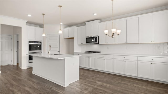 kitchen with sink, white cabinetry, stainless steel appliances, an island with sink, and decorative light fixtures