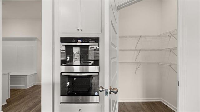 kitchen with crown molding, dark hardwood / wood-style flooring, double oven, and white cabinets