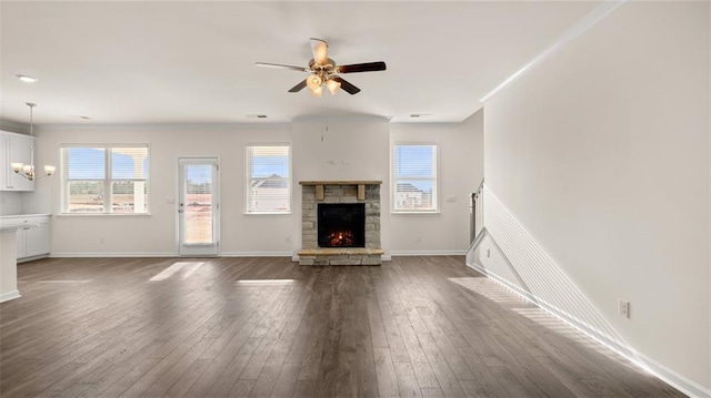 unfurnished living room with crown molding, ceiling fan with notable chandelier, a fireplace, and dark hardwood / wood-style flooring