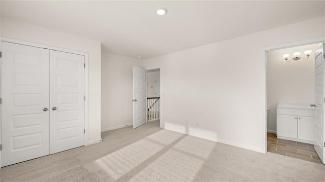 bedroom with light colored carpet, ensuite bath, and a closet