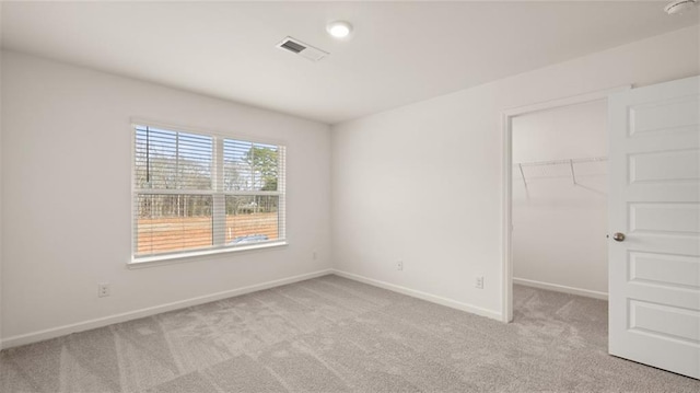 unfurnished bedroom featuring light colored carpet, a spacious closet, and a closet