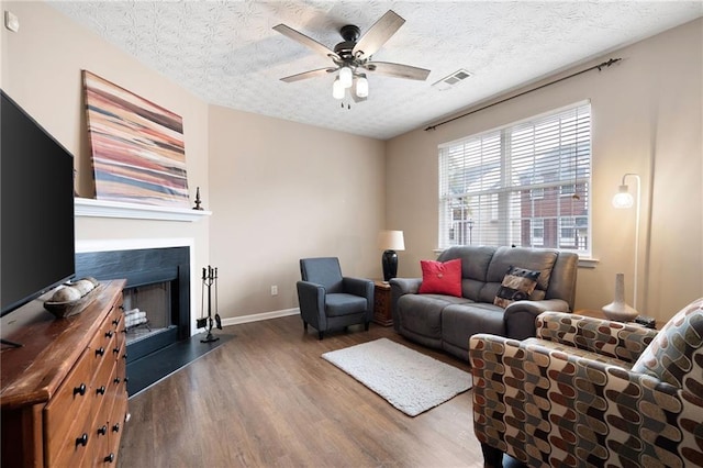 living room with hardwood / wood-style flooring, ceiling fan, and a textured ceiling