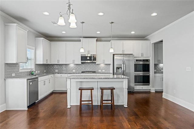 kitchen featuring crown molding, stainless steel appliances, a kitchen island, and white cabinets