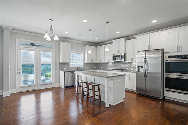 kitchen with tasteful backsplash, dark wood-style floors, appliances with stainless steel finishes, a breakfast bar, and a center island