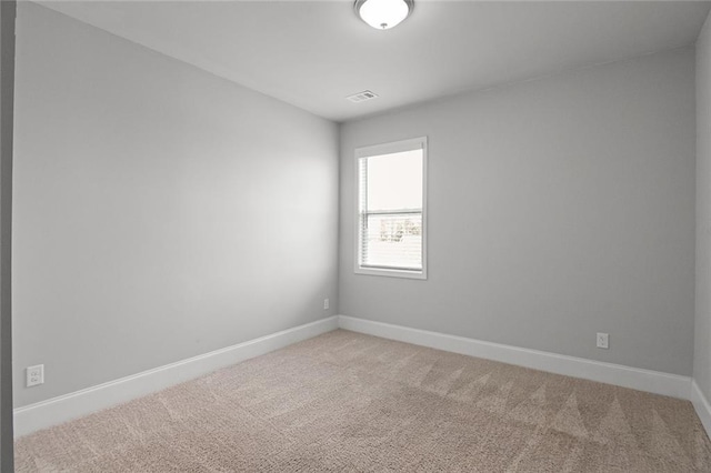 spare room featuring baseboards, visible vents, and light colored carpet