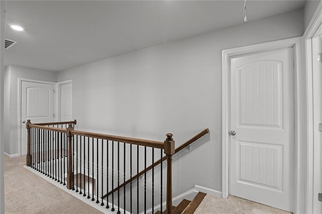 hallway with visible vents, carpet flooring, an upstairs landing, and baseboards