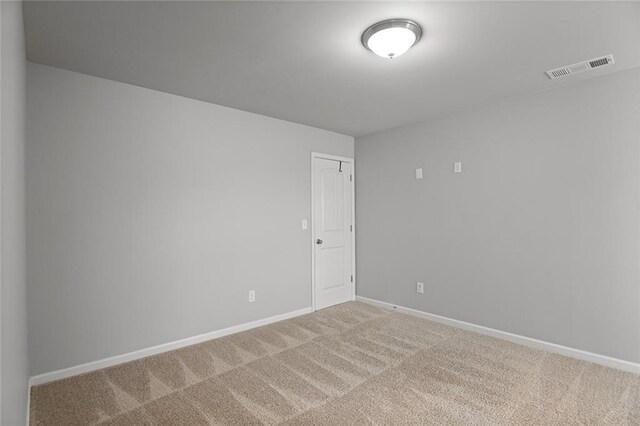 empty room with carpet floors, visible vents, and baseboards