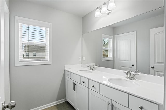 full bathroom featuring double vanity, baseboards, and a sink